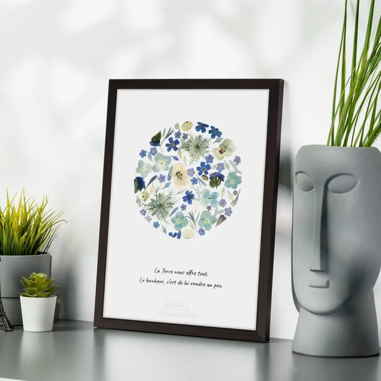 boule herbier en forme de lune pleine, de fleurs bleues pressées, cadre bois foncé et citation sur la terre