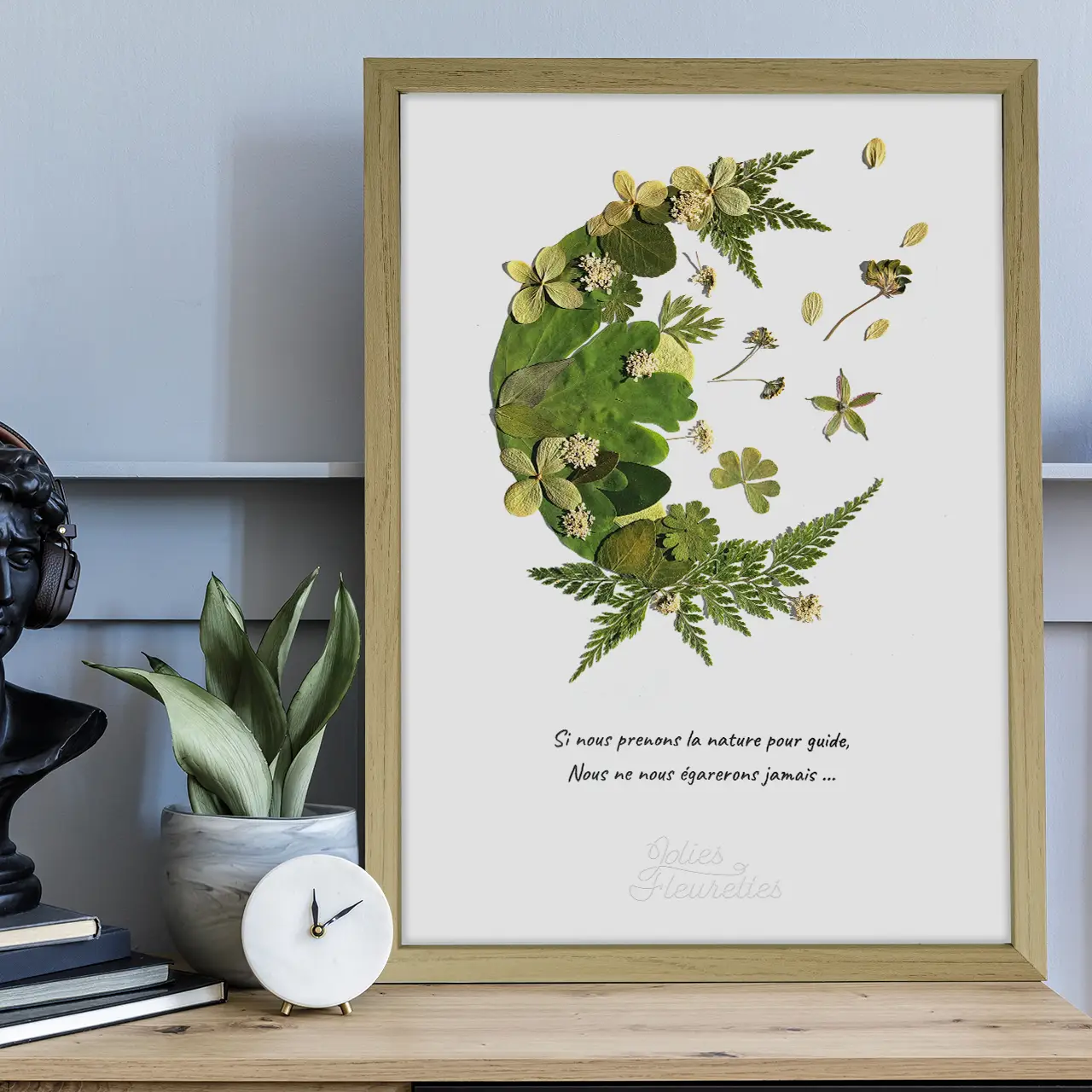 sur cadre bois clair, herbier demi lune de végétaux vert avec citation sur la nature