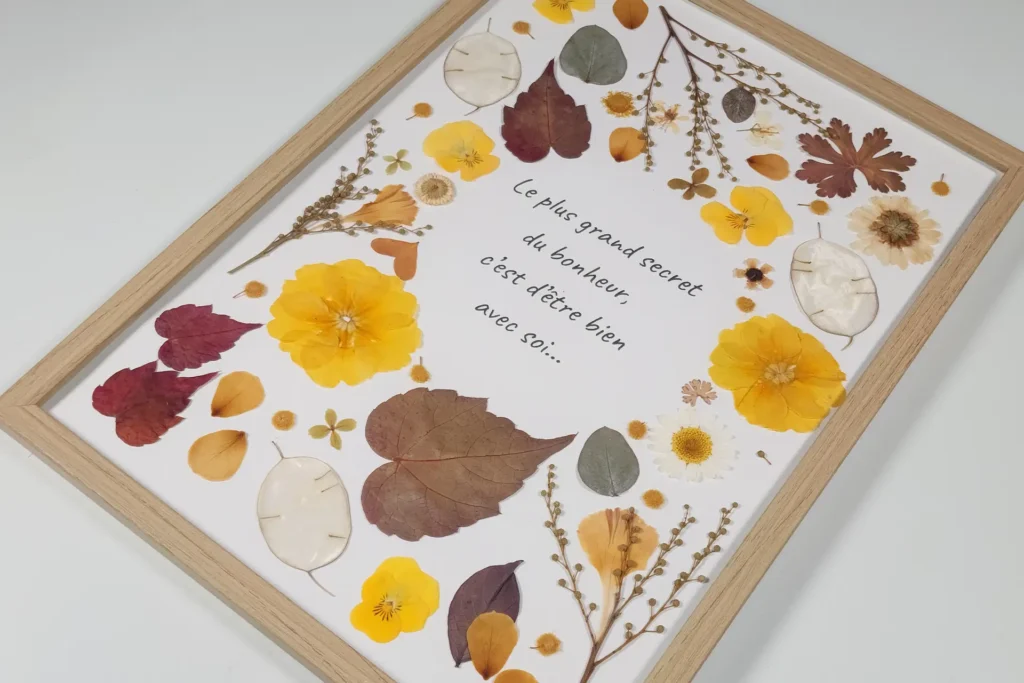 cadre et création florale de fleurs pressées ton automnal jaune orangé, entourant une citation de motivation en cadre A4 bois naturel