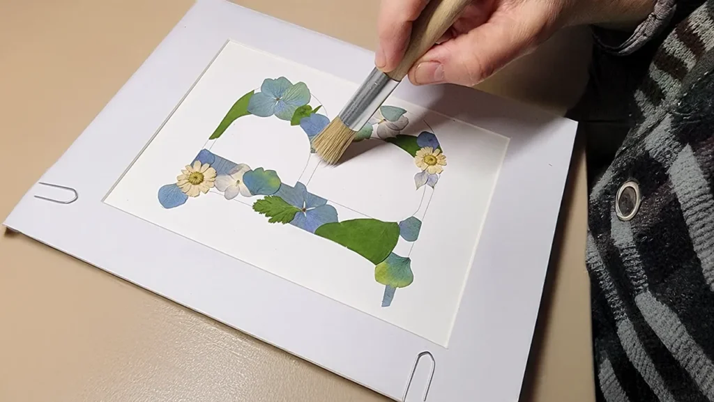 artiste entrain de créer une lettre B en herbier de couleur bleu et vert